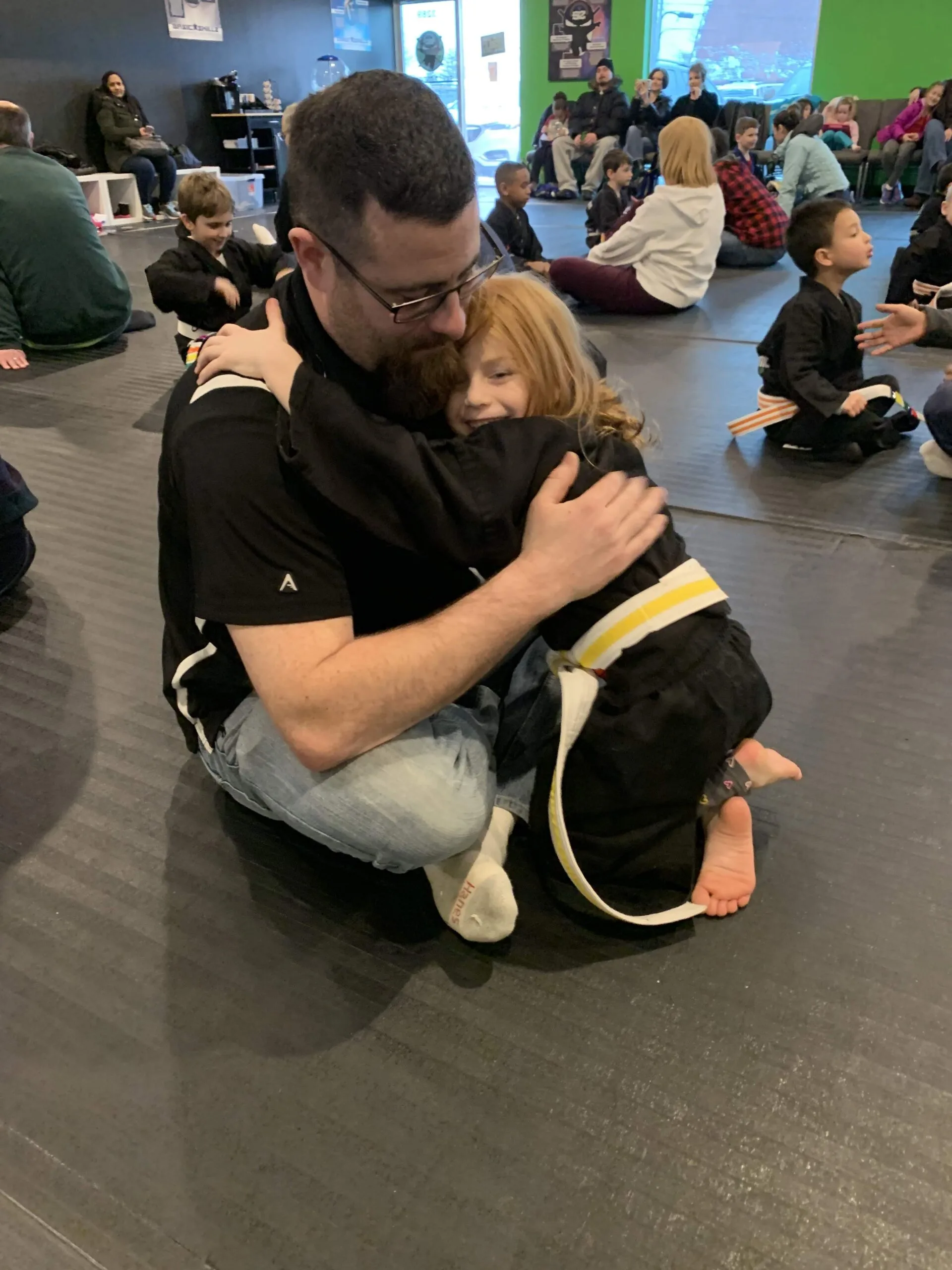 young girl hugging her dad in karate class