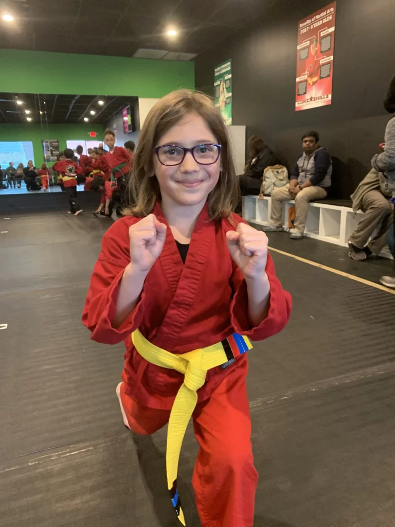 a girl smiling in a karate pose.