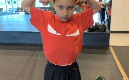 a boy posing in karate class with red shirt and black pants