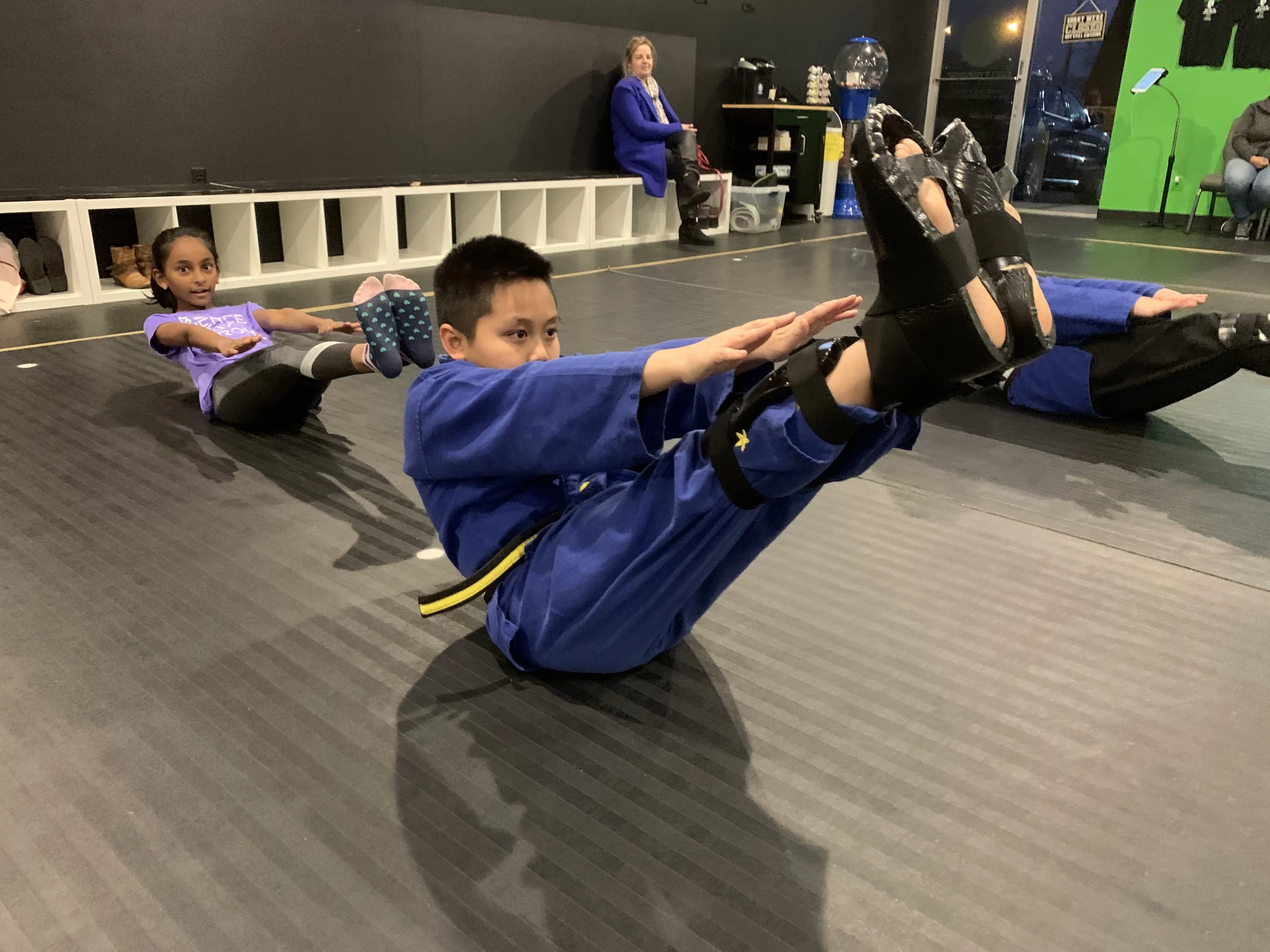 a boy doing v-situps in karate class