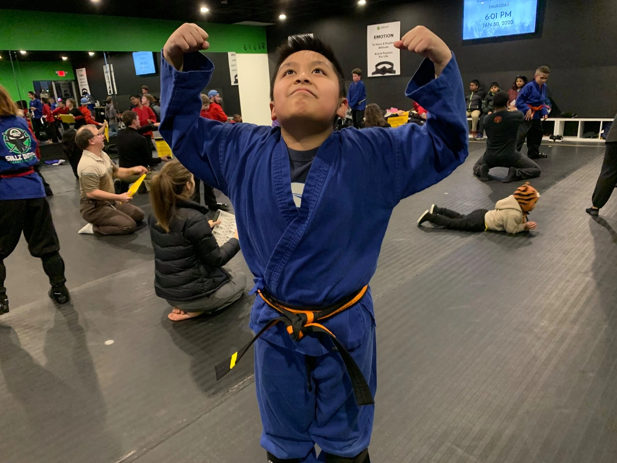 boy shows off muscles in karate class.